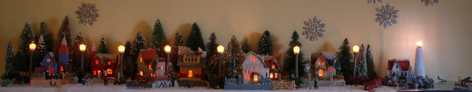 Antique Christmas cardboard house putz (village) on fireplace mantel at night (70K)