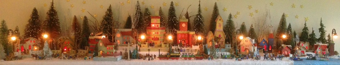 Antique Christmas cardboard house putz (village) on fireplace mantel at night (105K)