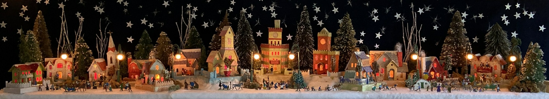 Antique Christmas cardboard house putz (village) on fireplace mantel at night (280K)