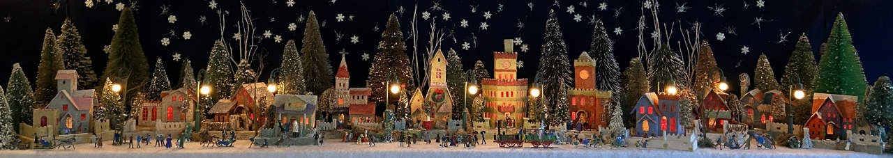 Antique Christmas cardboard house putz (village) on fireplace mantel at night (105K)