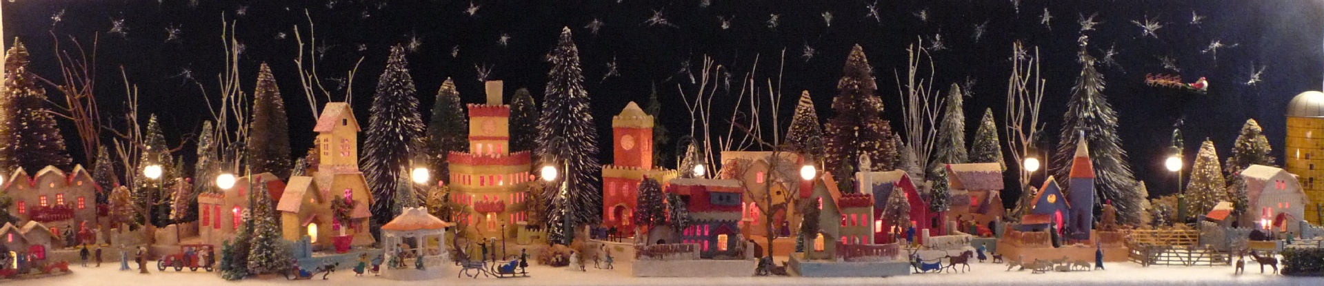 Antique Christmas cardboard house putz (village) on fireplace mantel at night (200K)