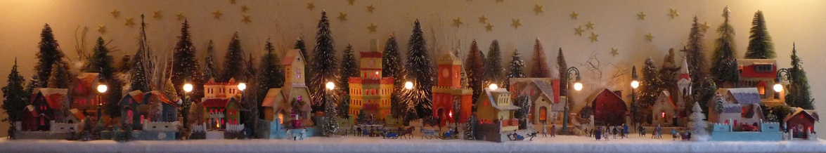 Antique Christmas cardboard house putz (village) on fireplace mantel at night (105K)